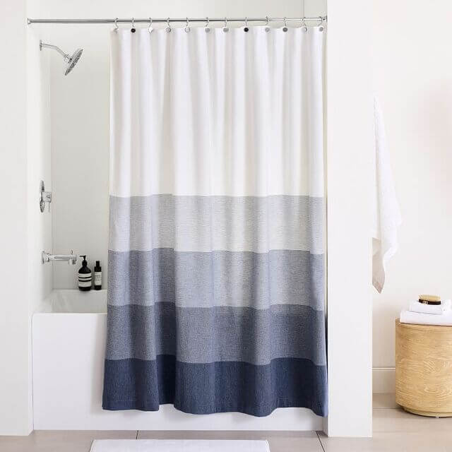 Una cortina de ducha con un estampado de rayas en varios tonos de azul y blanco